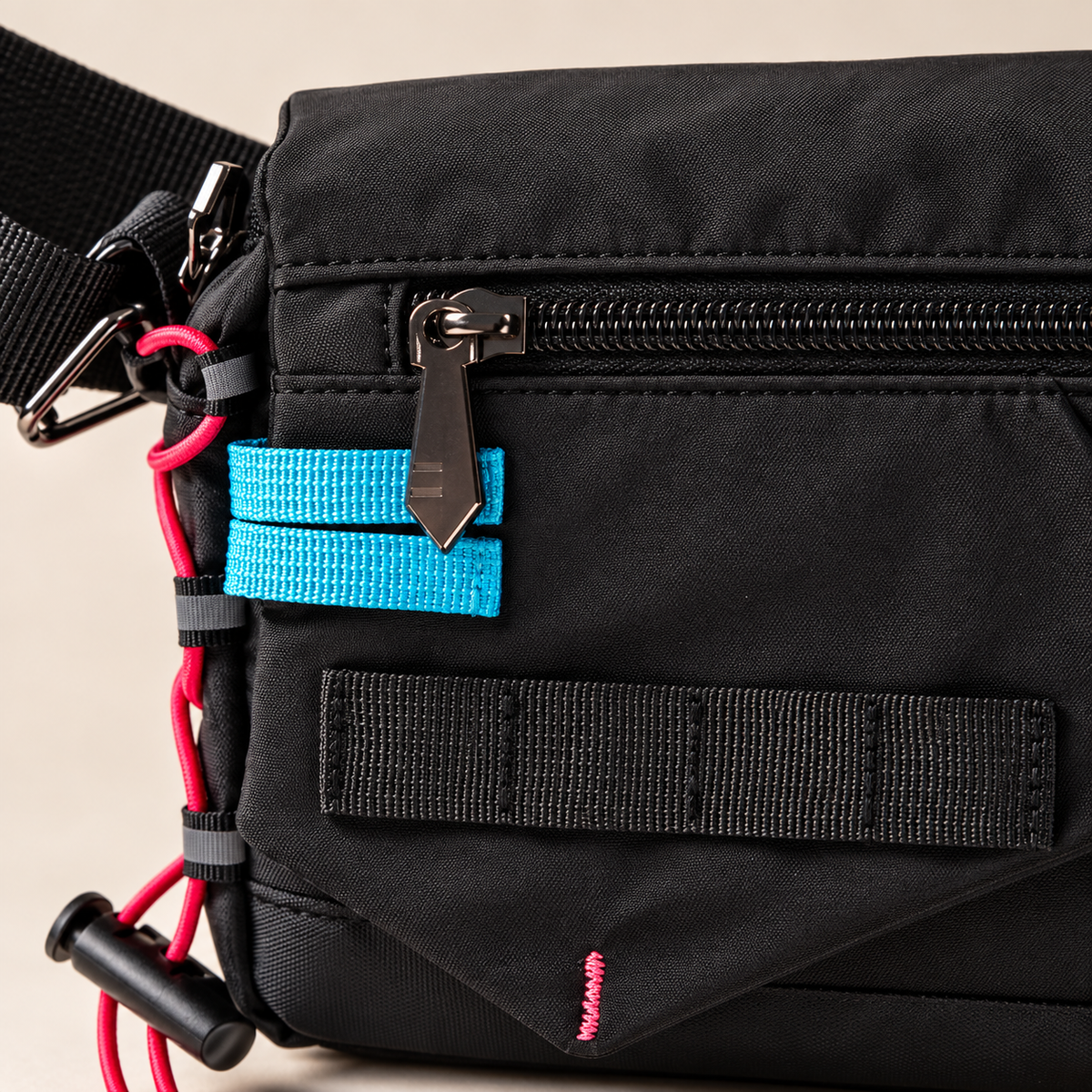Black bag front zipper, cyan webbing and pink cord detail